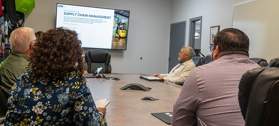 Associates sit in a conference room reviewing ASW Global's Supply Chain Management presentation.