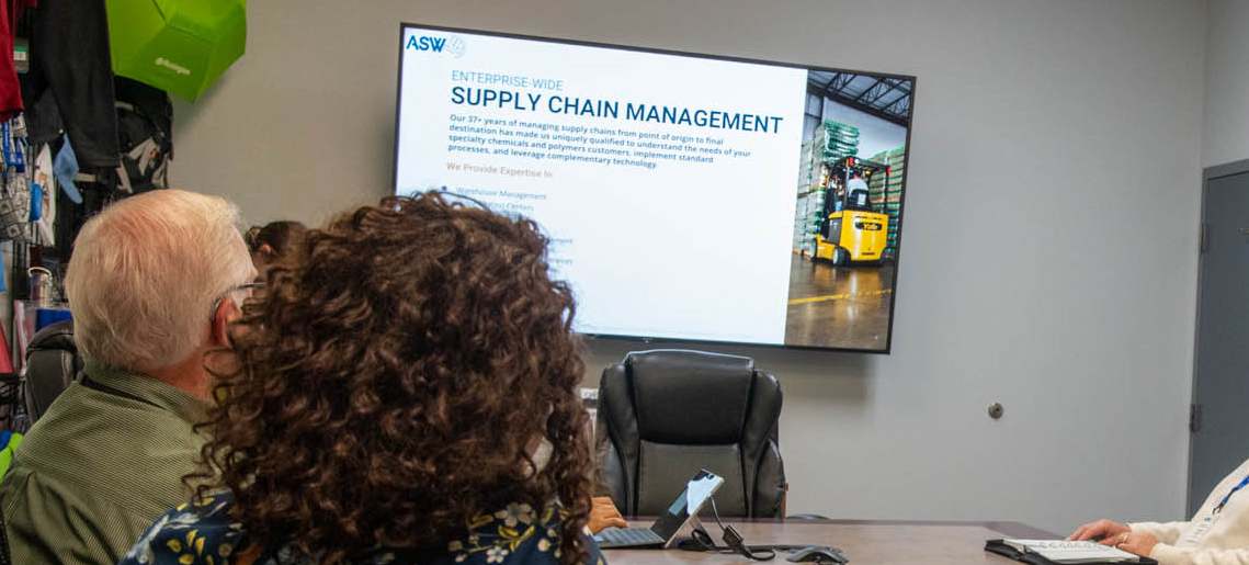 Associates sit in a conference room reviewing ASW Global's Supply Chain Management presentation.