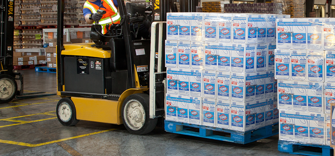 A forklift begins to lift retail product in a distribution center