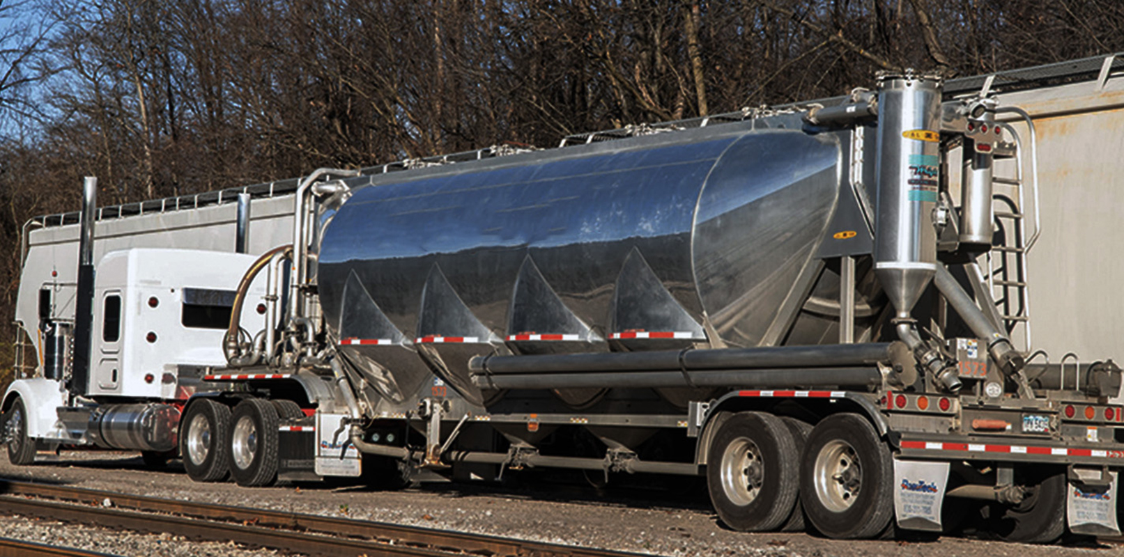 A bulk pneumatic tanker lines up next to a hopper car for bulk transloading of polymer