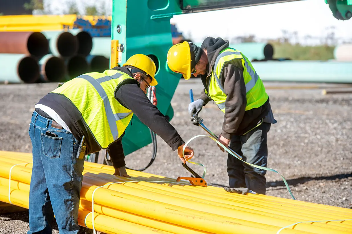 ASW Energy Services associates at ASW's pipe yard securing yellow HDPE pipe for the utility sector